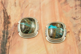 Genuine Sunnyside Turquoise set in Sterling Silver Post Earrings. The matrix on this rare stone is outstanding. The Sunnyside mine is located in northern Nevada near the town of Tuscarora in the Tuscarora mountain range. The mine is no longer in operation as it has become part of a gold mining operation and a privately owned ranch. The Sunnyside mine was mined mostly in the 70's. You won't find much of this great turquoise around anymore except for old stashes. Created by Navajo Artist Larson Lee. Signed.

